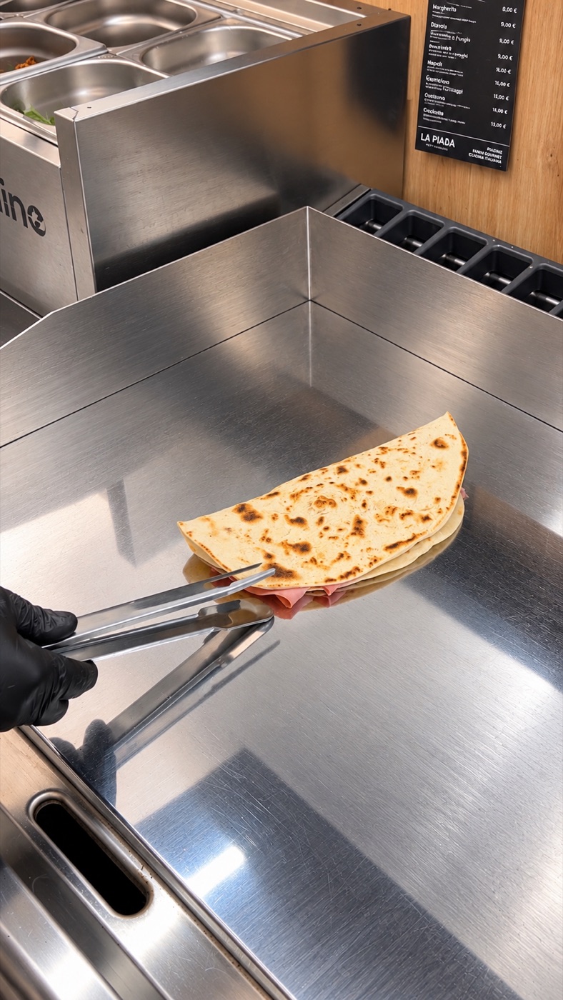 Gefüllte Piadina mit Schinken wird auf der Platte gewendet